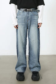 Paneled wide-leg denim trousers in medium wash with distressed side seams and a relaxed fit.
