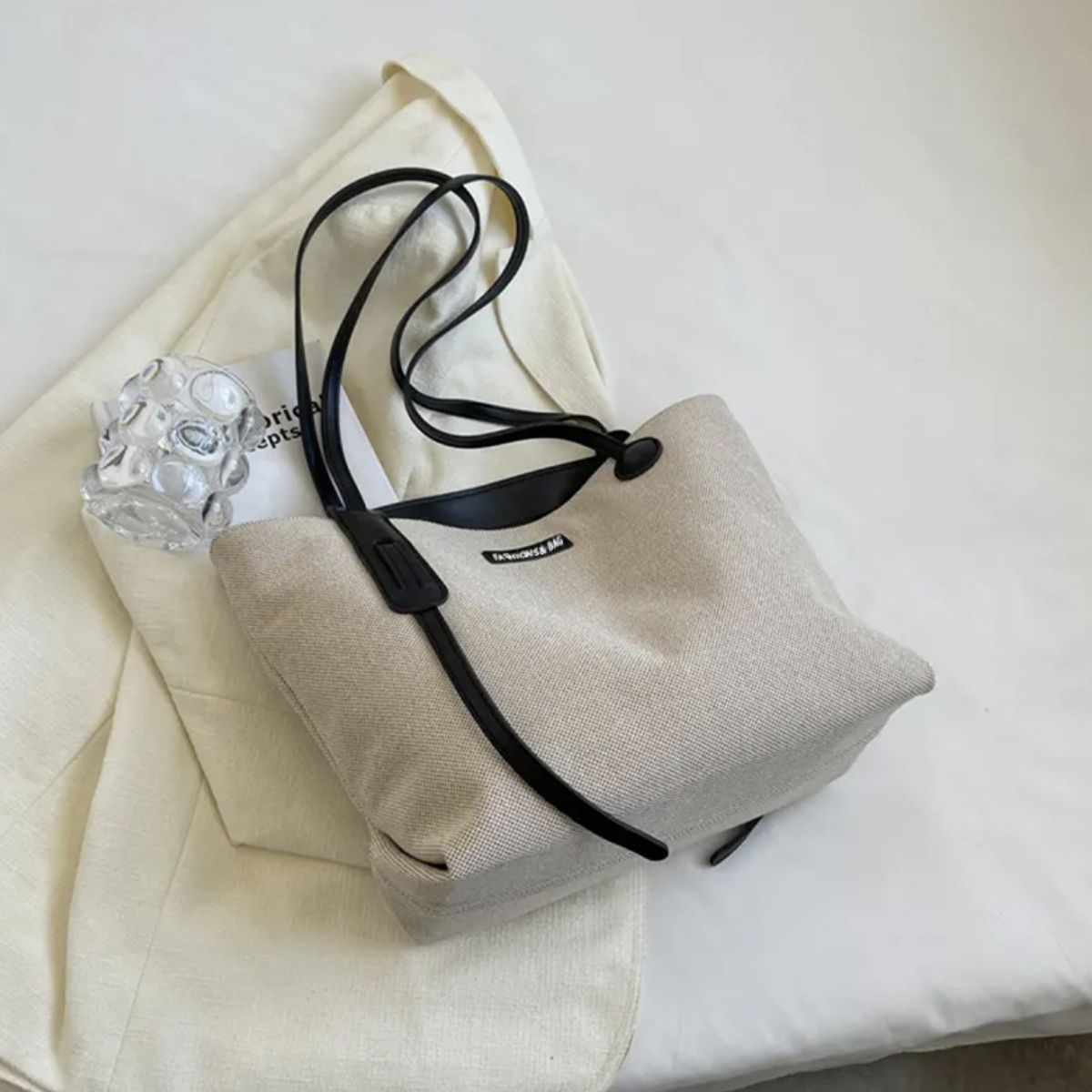 Large canvas shoulder bag with black leather trim and straps.