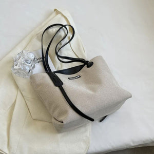 Large canvas shoulder bag with black leather trim and straps.