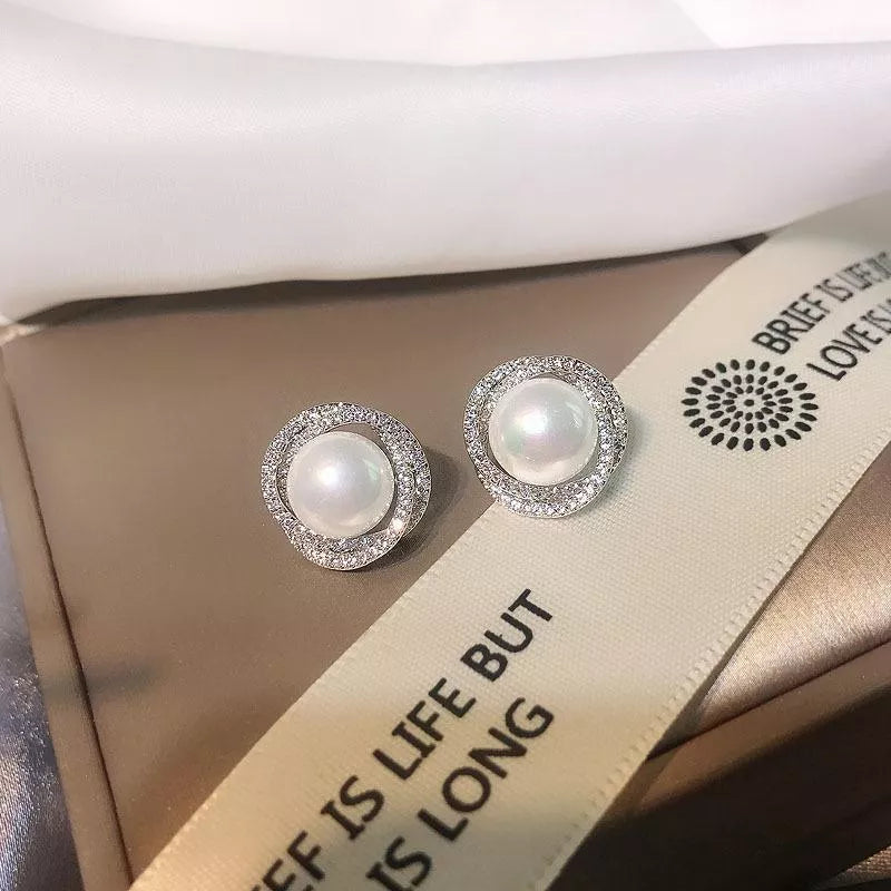 Elegant pearl and zircon stud earrings in silver with a halo of sparkling stones.