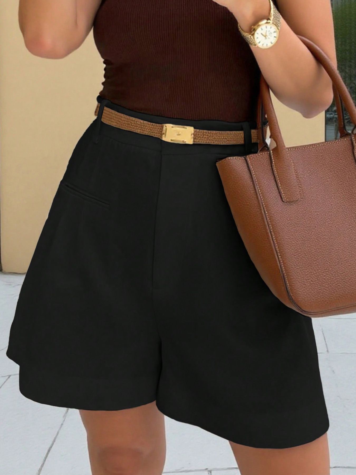 Black pleated high-waisted shorts with belt loops and pockets, styled with a brown belt and handbag.