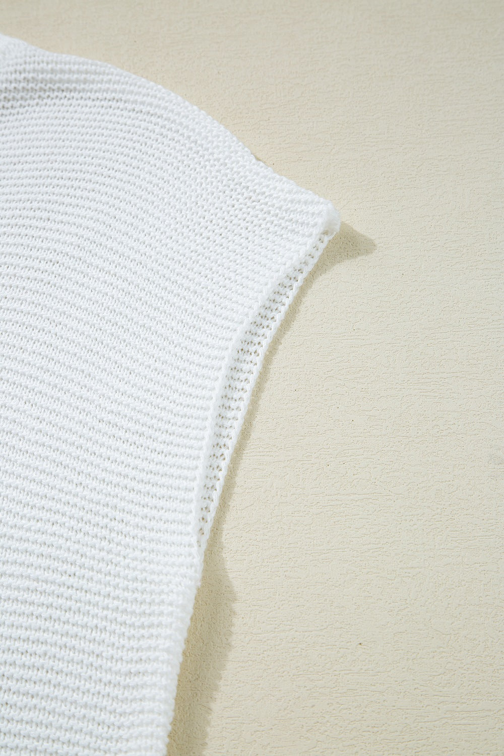 White knit crop top with a textured stitch and open weave detail on the sleeve hem.