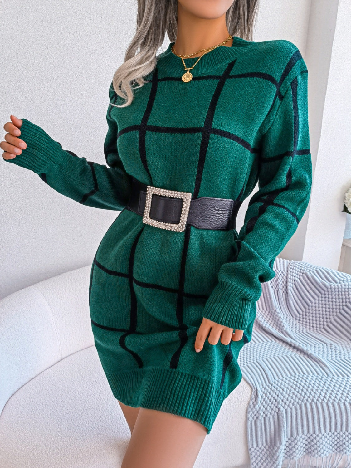 Dark green acrylic knit mini dress with black geometric grid pattern, crew neck, long sleeves, and a jeweled buckle belt.