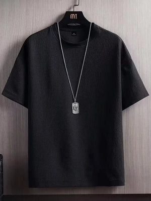 Textured black cotton t-shirt for men with round neck and short sleeves, styled with a pendant necklace.