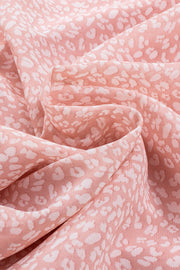 Blush pink sleeveless blouse with a white abstract animal print and ruffled neckline detail.