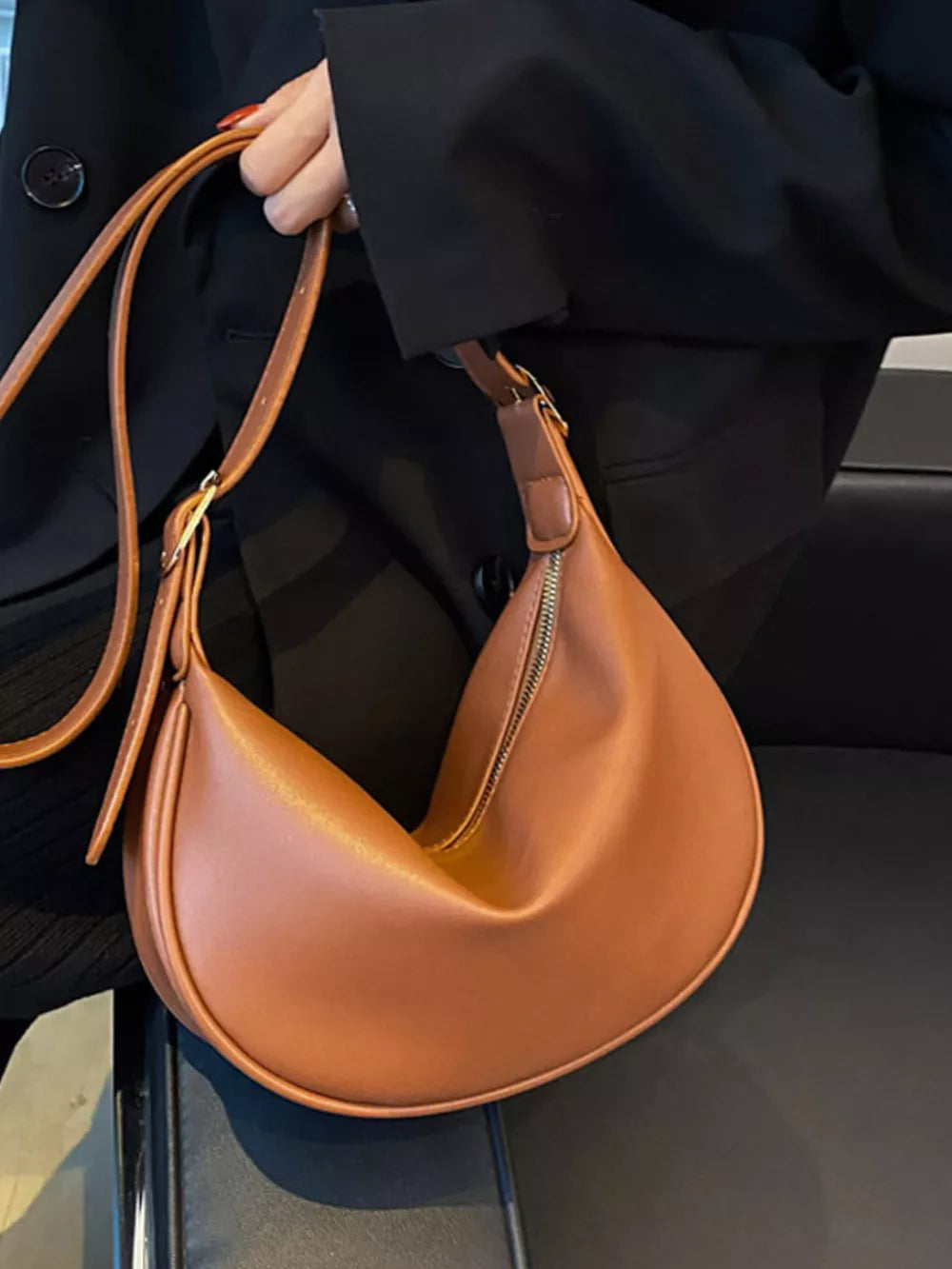 Brown minimalist crescent crossbody bag with adjustable strap and zipper detail