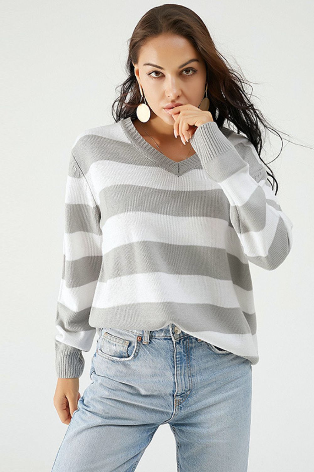 Gray and white striped V-neck relaxed knit sweater with long sleeves.