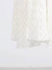 White lace maxi dress with a textured diamond pattern and ruffled hem detail.