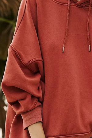 Oversized rust washed cotton hoodie with drawstring hood and cuffed sleeves.