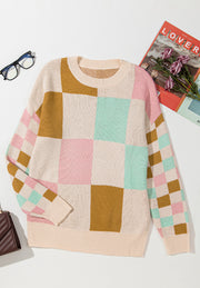Colorblock checkerboard knit sweater with crew neck and long sleeves in blush pink, beige, and mustard yellow.