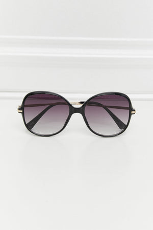 Oversized black round frame sunglasses with gradient lenses and gold accents.