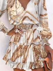 Tiered mini dress with abstract speckled pattern, V-neck, long sleeves, and ruffled hem.