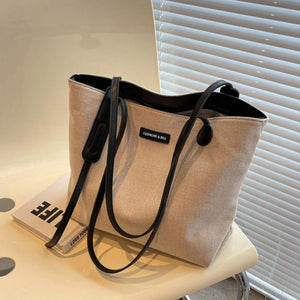 Large canvas shoulder bag in coffee color with black leather trim and handles.
