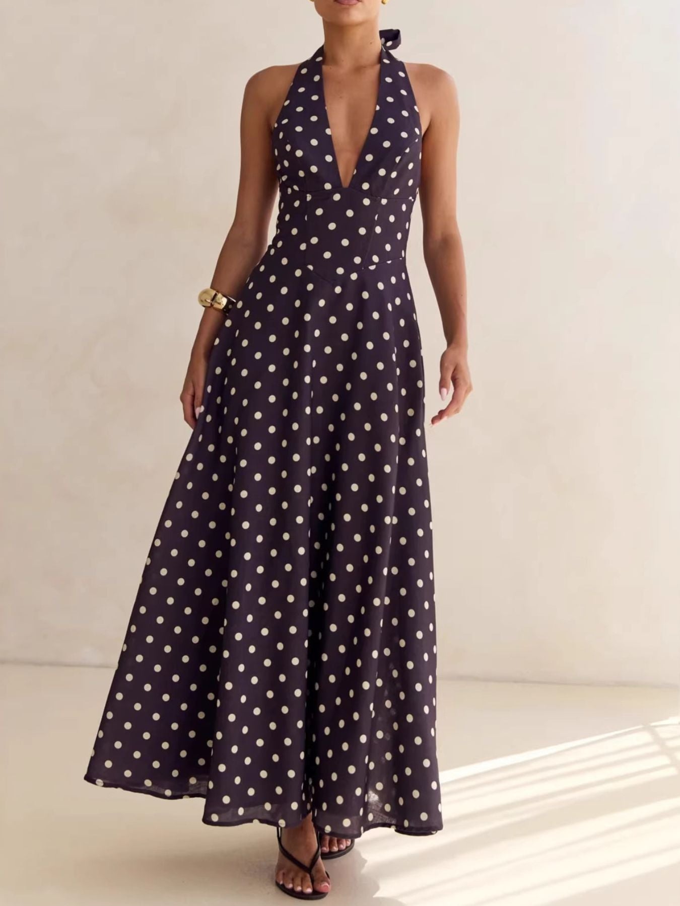 Maxi dress with halter neck, deep V-neck, and polka dot pattern in dark blue.
