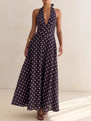 Maxi dress with halter neck, deep V-neck, and polka dot pattern in dark blue.