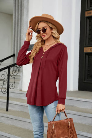 Burgundy hooded henley top with button detail and drawstring, long sleeves, and pleated front.