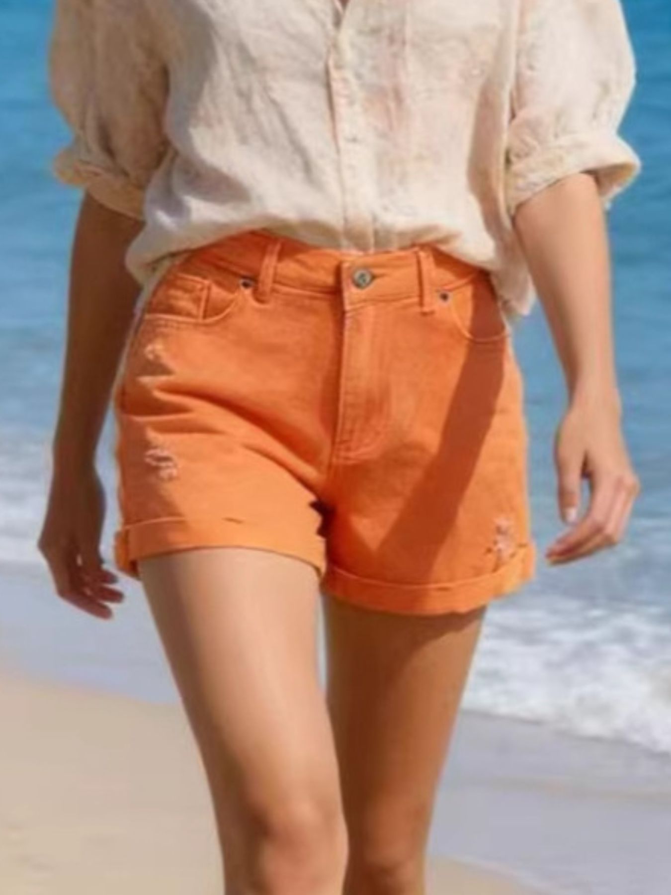Orange-red distressed cuffed denim shorts with a high waist.
