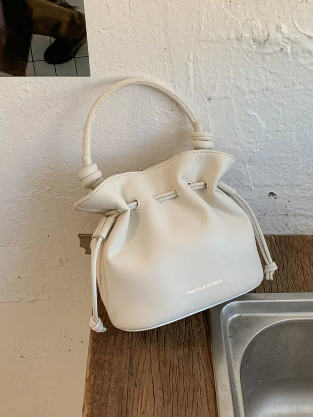 White pu leather cinch-top crossbody bag with knotted handle detail