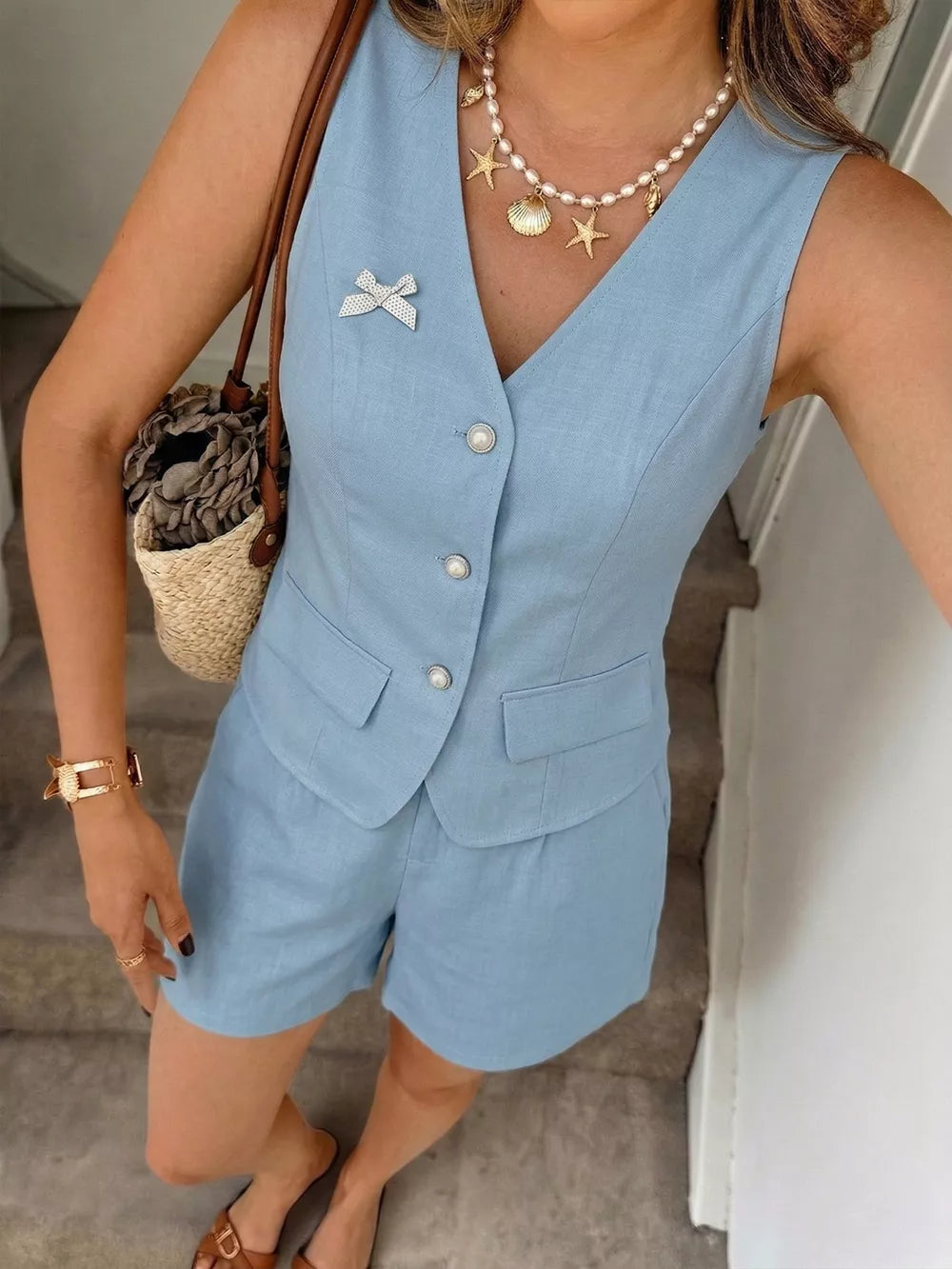 Chic blue buttoned vest and tailored shorts set with pearl buttons and a bow pin detail.
