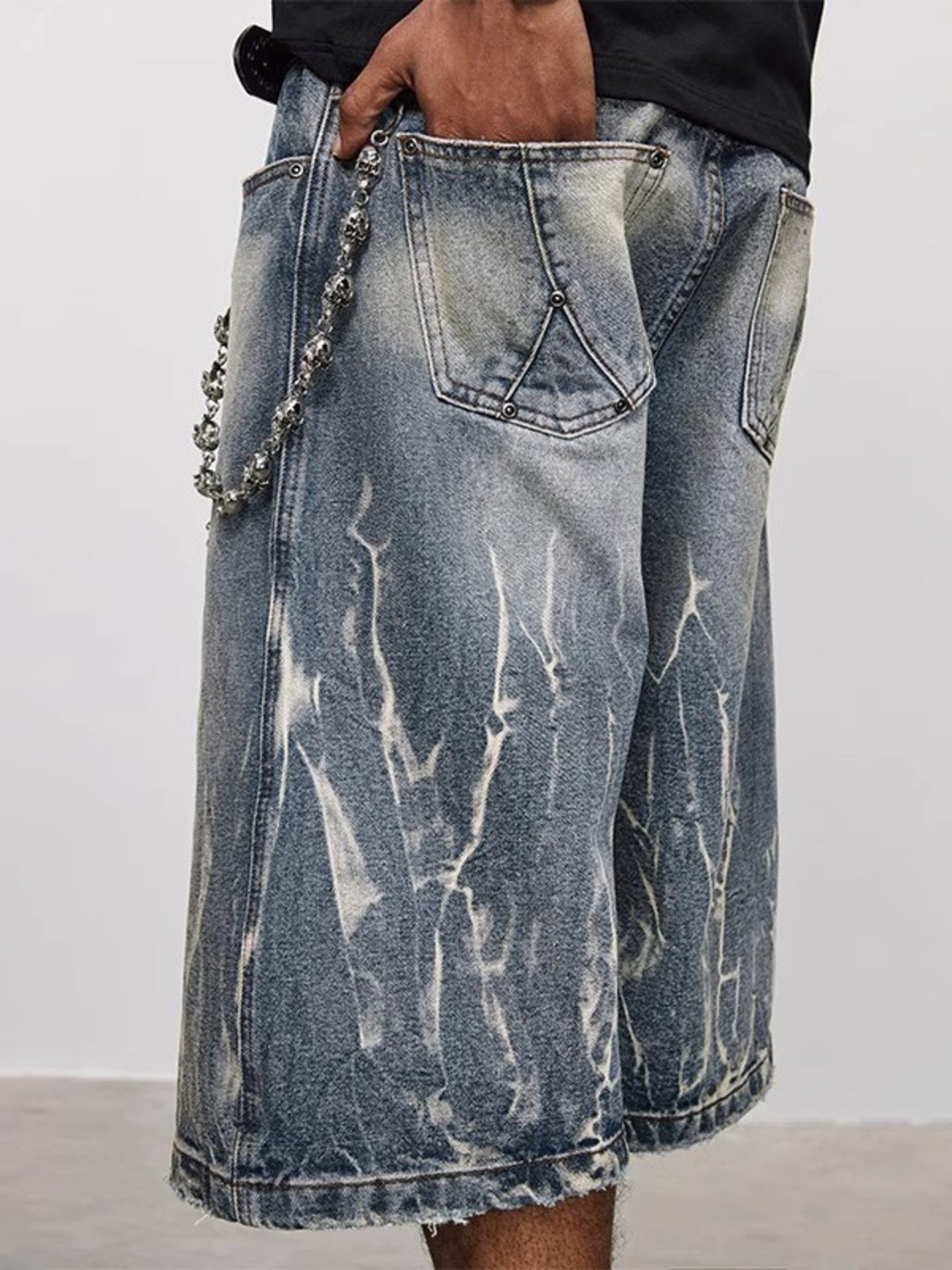 Men's loose fit blue denim shorts with white distressed wash and skull chain detail.