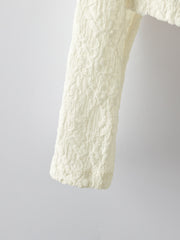 Cream lace button-up cardigan with textured floral pattern detail.