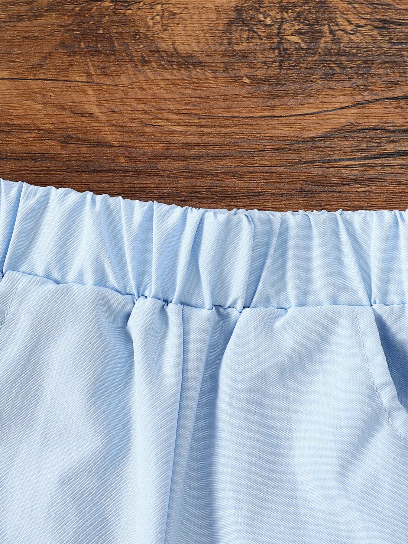 Light blue cotton baby shorts with elastic waistband and pocket detail.