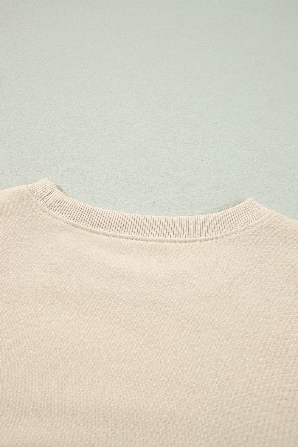 Cream sweatshirt with ribbed neckline and subtle shoulder ruffles.