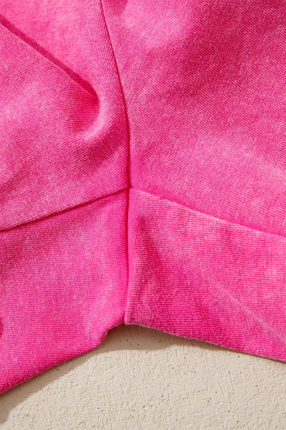 Acid-washed hot pink cotton drawstring shorts with pockets, close-up detail.