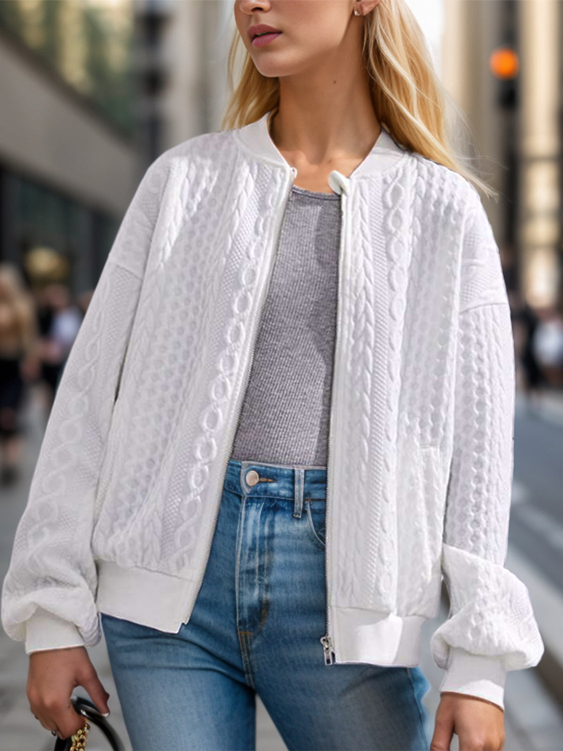 White cable knit bomber jacket with a zip front and ribbed cuffs.