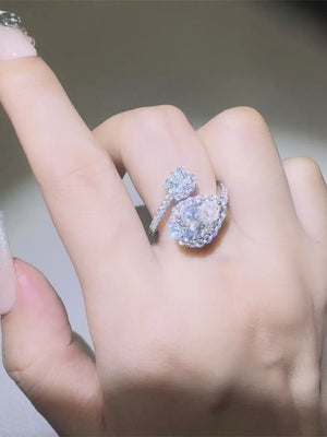 Silver bypass ring with halo and pear-shaped center stone, adorned with small diamonds.