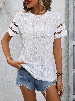 White eyelet blouse with scalloped short sleeves and intricate patterned fabric.