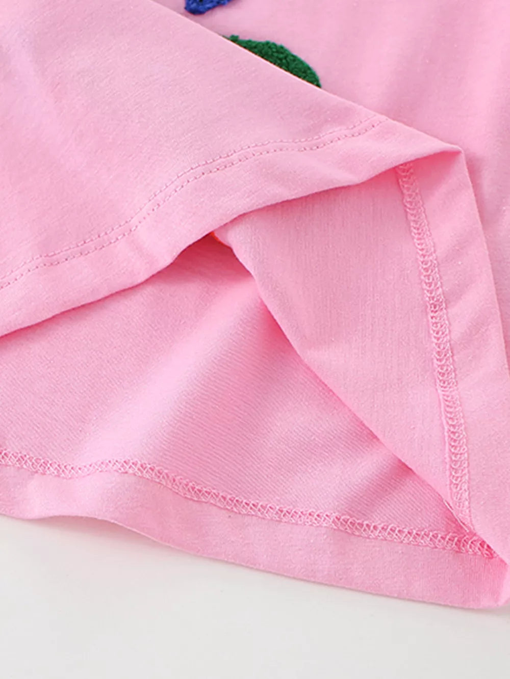 Pink cotton t-shirt with embroidered ocean creature detail and visible stitching.