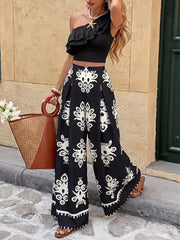Black one-shoulder ruffled crop top with black and white printed wide-leg pants.
