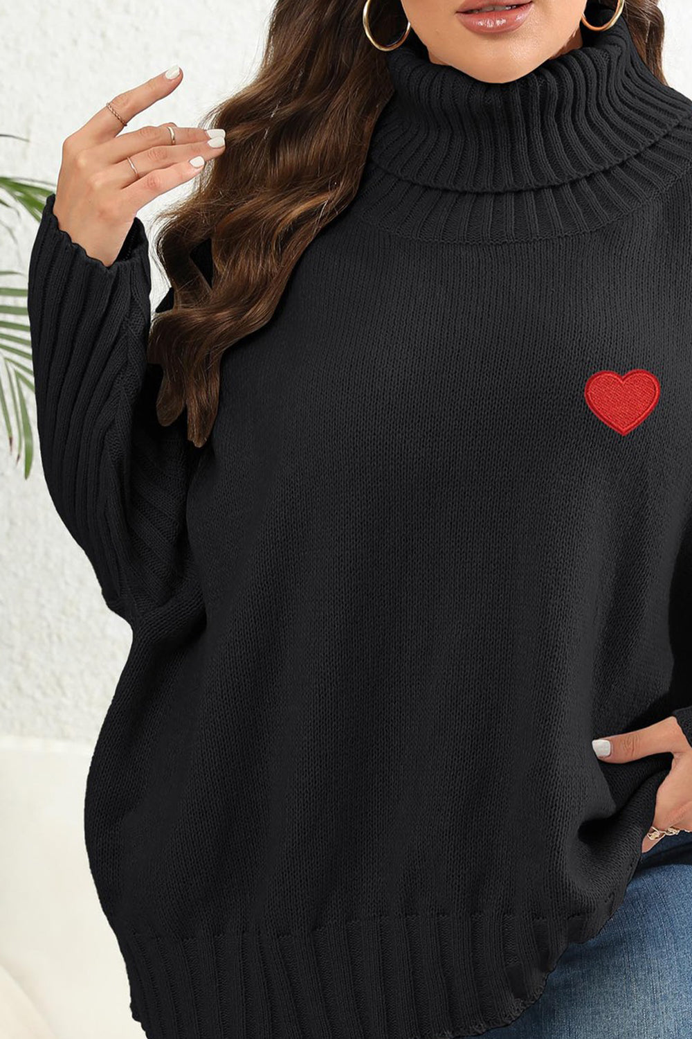 Black turtleneck sweater with red heart appliqué and ribbed sleeves.