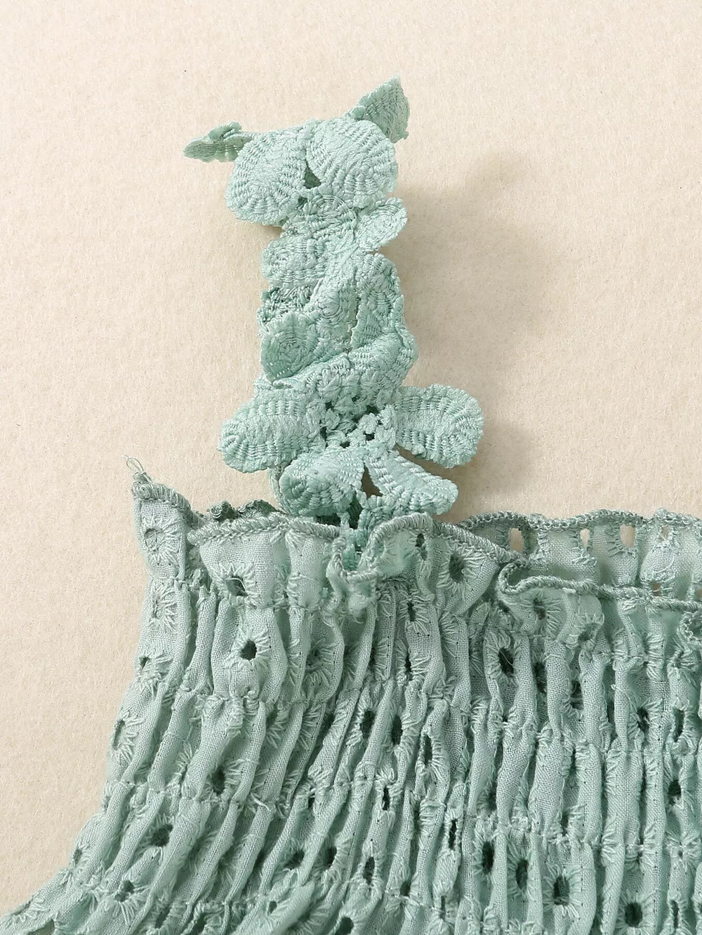 Green cotton eyelet tank top with smocking and floral strap detail.