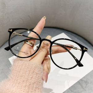 Black translucent round frame eyeglasses with gold accents on temples.
