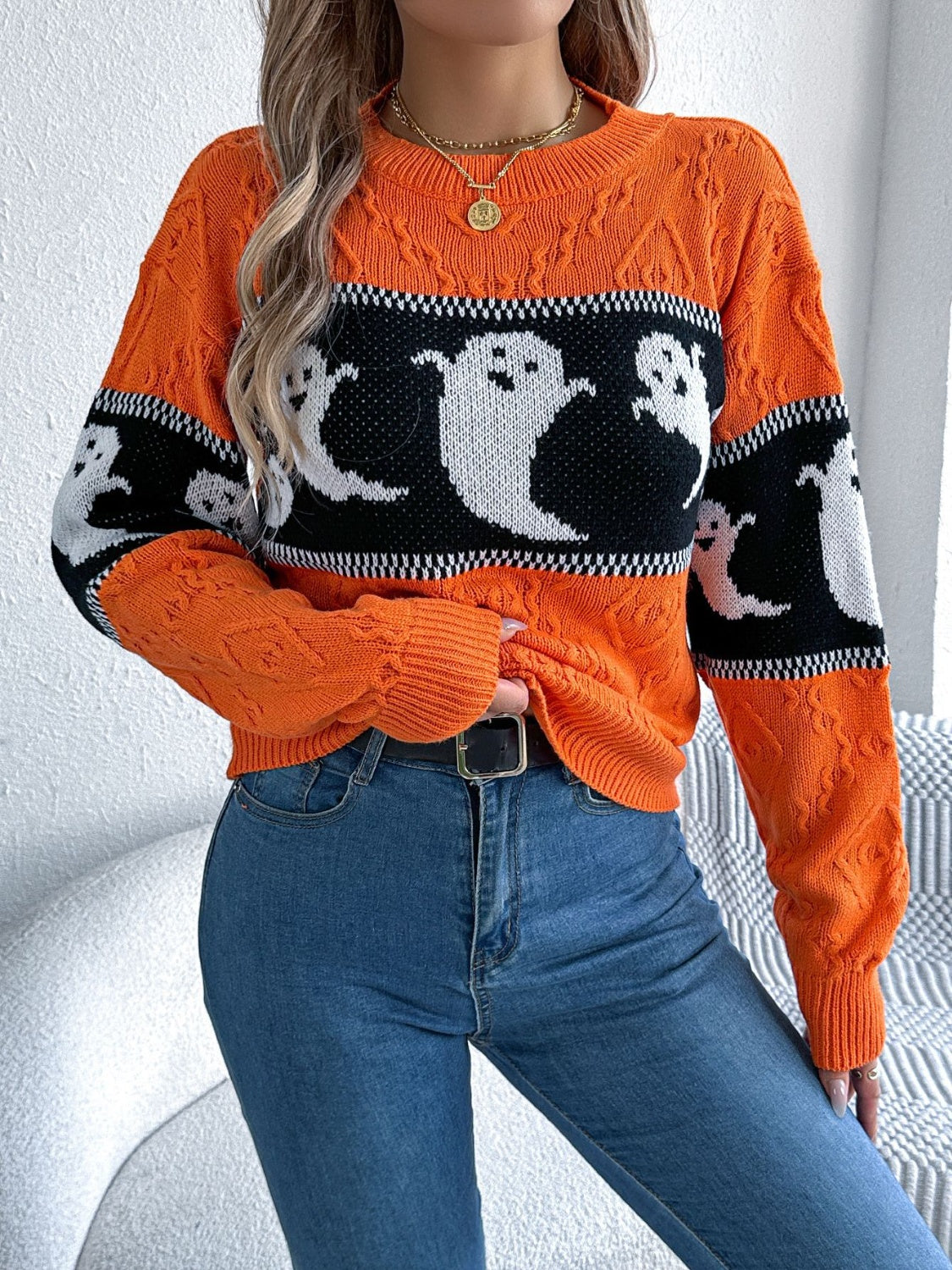 Orange cable knit crewneck sweater with ghost motif and black band detail