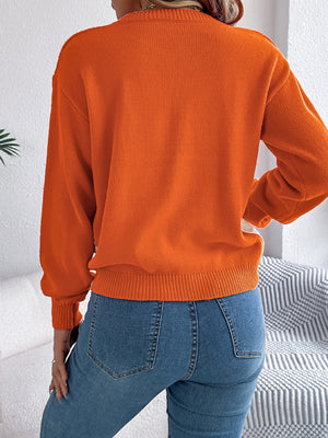 Orange acrylic cable knit sweater with contrast detail and ribbed trim.