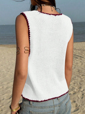 White knit sweater vest with dark red trim and scalloped hem.
