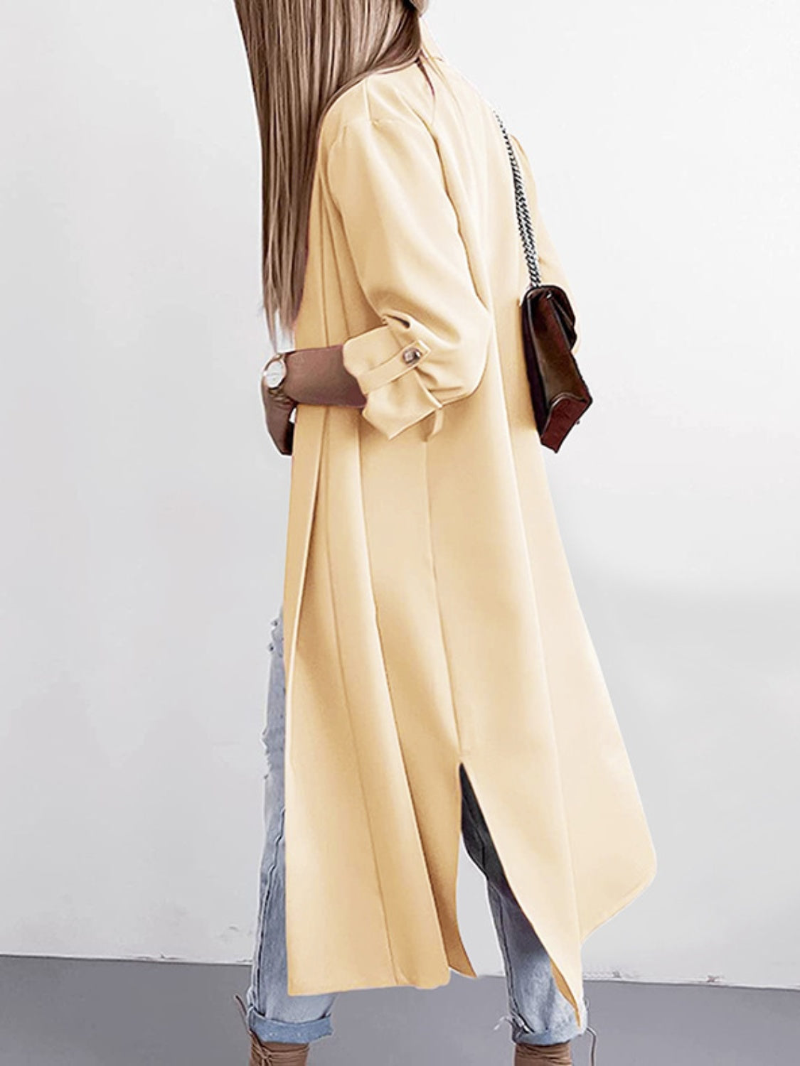 Pastel yellow draped-front maxi trench coat with button cuffs and side slits.