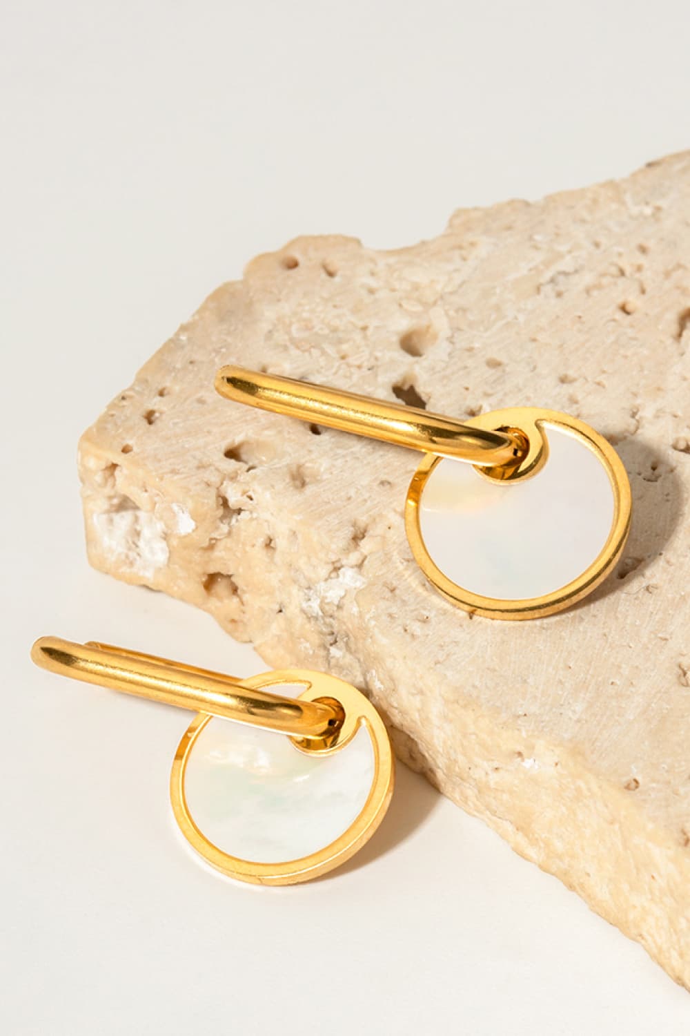 Gold mother-of-pearl disc drop earrings with a modern dangle design.