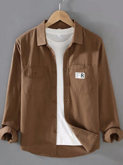 Brown cotton long-sleeve overshirt with two chest pockets and buttoned front.