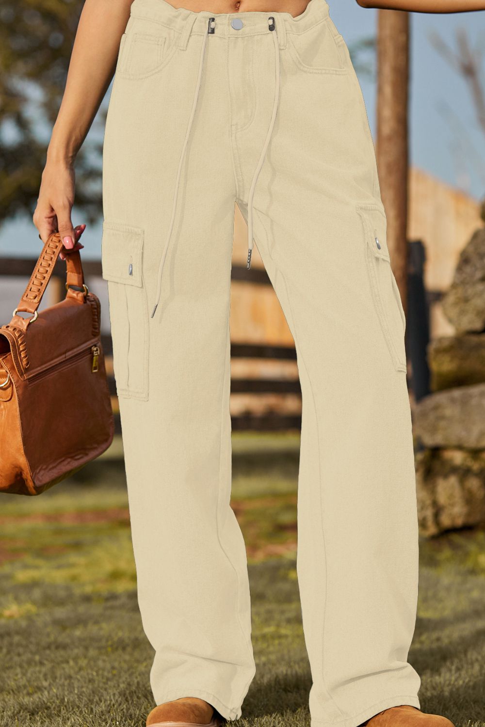 Tan utility denim cargo pants with drawstring waist and button closure.