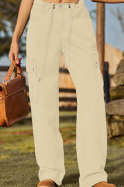 Tan utility denim cargo pants with drawstring waist and button closure.