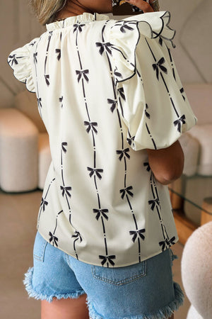 Ivory blouse with black bow print, ruffled neckline and sleeves.