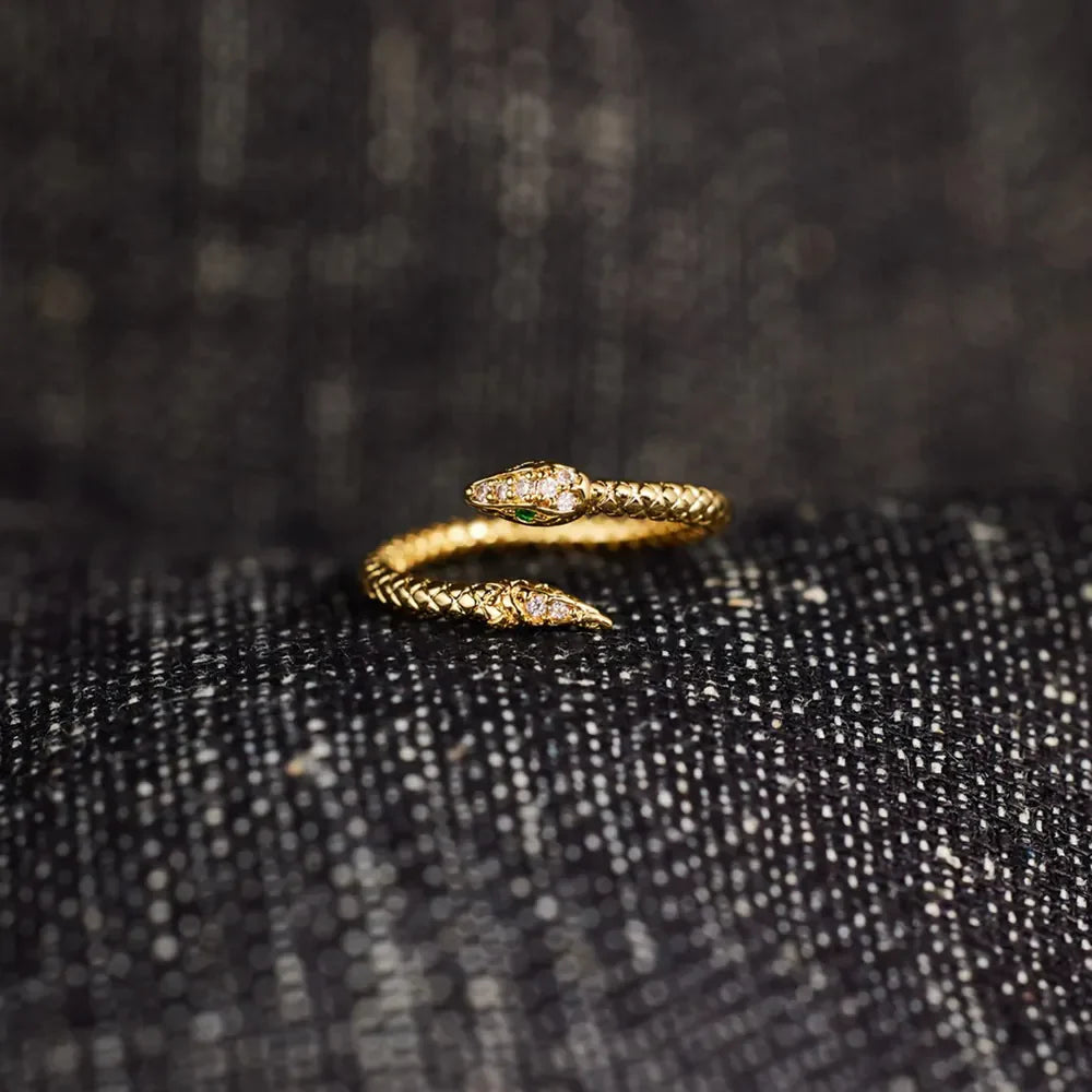 Gold bypass snake ring with diamond accents and green eye detail