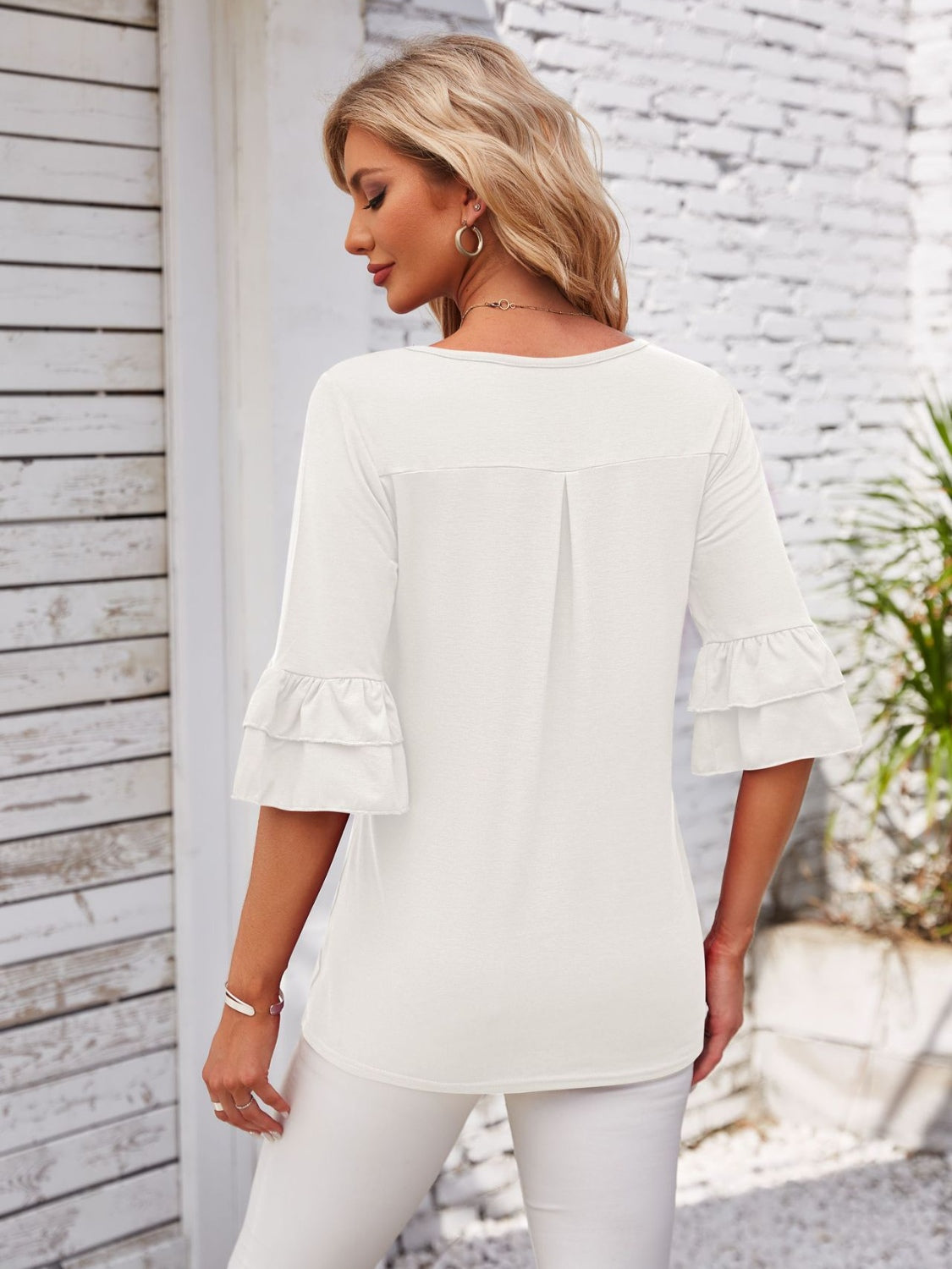 White blouse with ruffled sleeves and a pleated back detail.