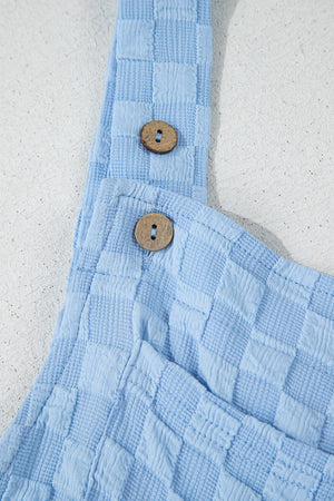 Light blue textured checkered jumpsuit with button straps and wooden buttons.