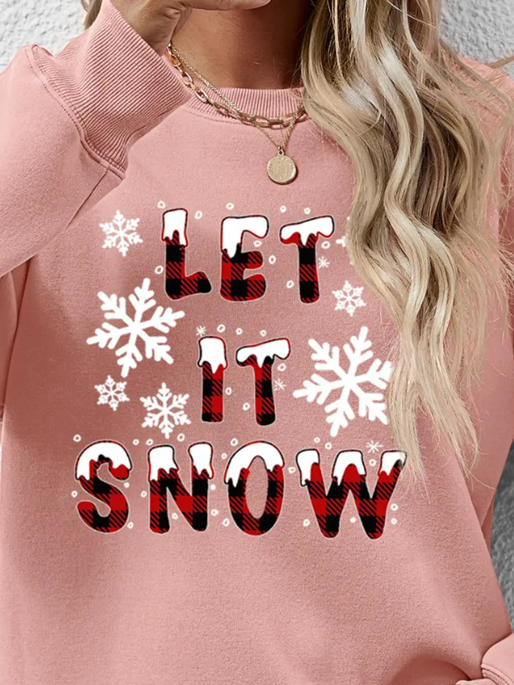 Blush pink crewneck sweatshirt with "Let It Snow" graphic and snowflakes