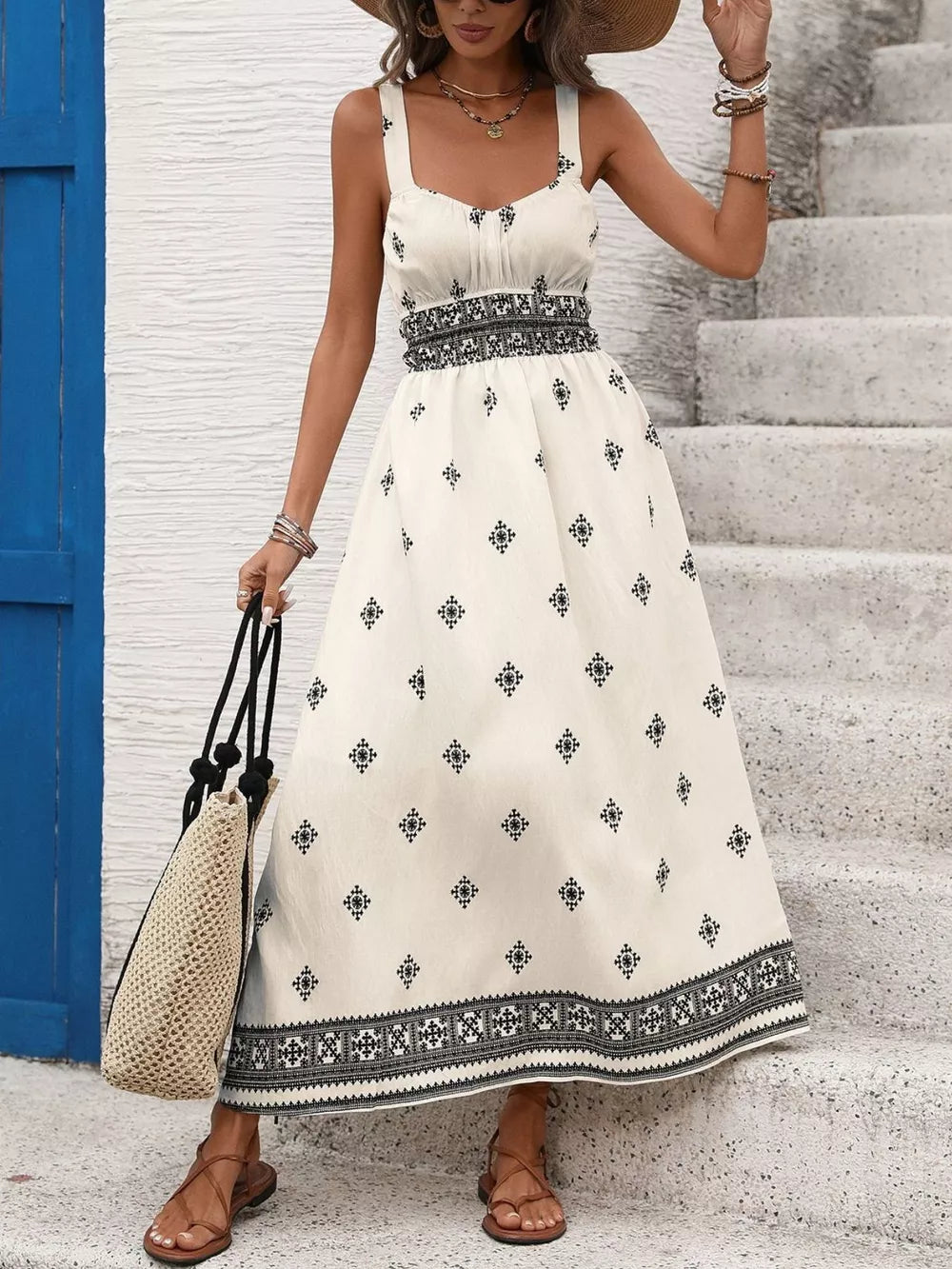 White midi dress with black geometric print, wide straps, smocked waist, and A-line skirt.